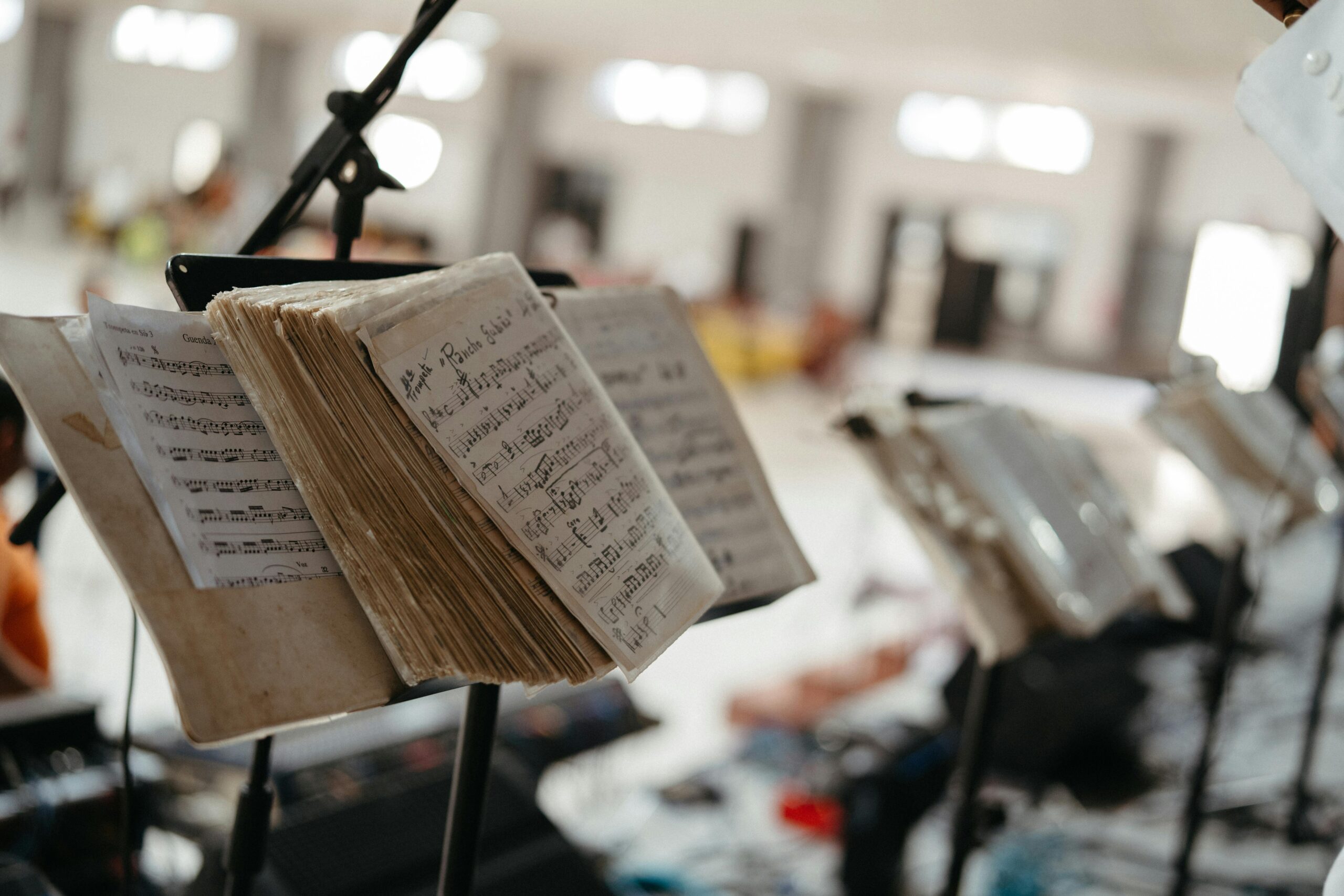 Detailed view of music sheets on a stand in an indoor concert setting with blurred background.